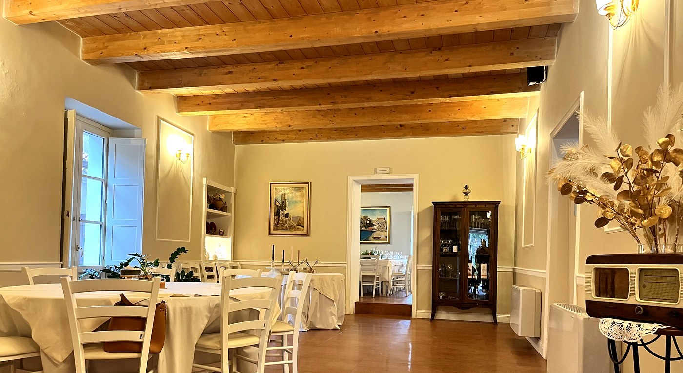 Sale interne del palazzo L'800 Locanda a Palazzo con travi in legno e tavoli apparecchiati